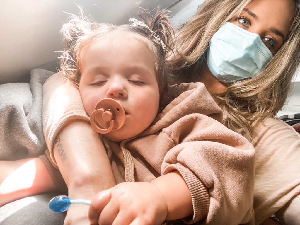 toddler sleeping on airplane in moms lap with pacifier and sucker